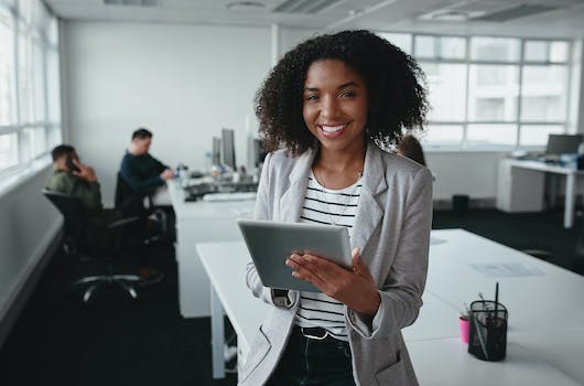 Woman holding an ipad smiling in office